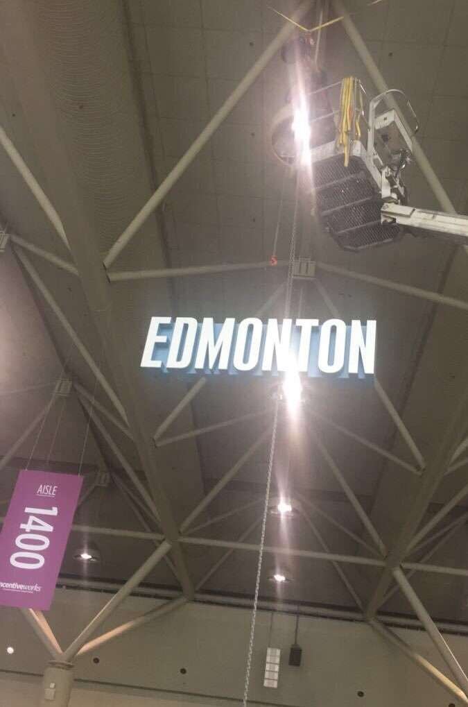 Boom lift mounting hanging trade show sign off the ceiling.