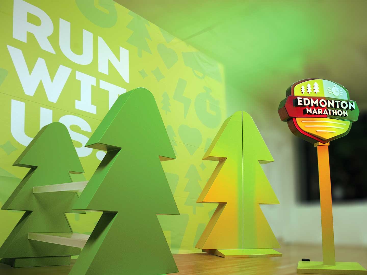 Finished display booth for trade shows with tree shaped displays, a 3 dimensional logo and a printed backdrop reding "run with us".