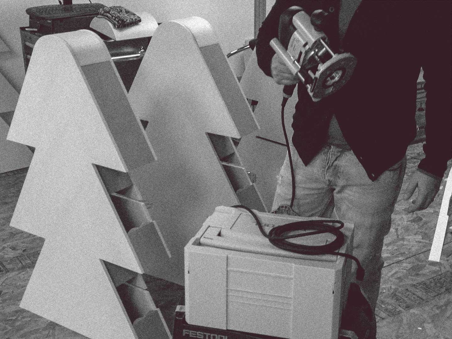 Man holding a router during custom trade show booth fabrication of tree shaped displays.