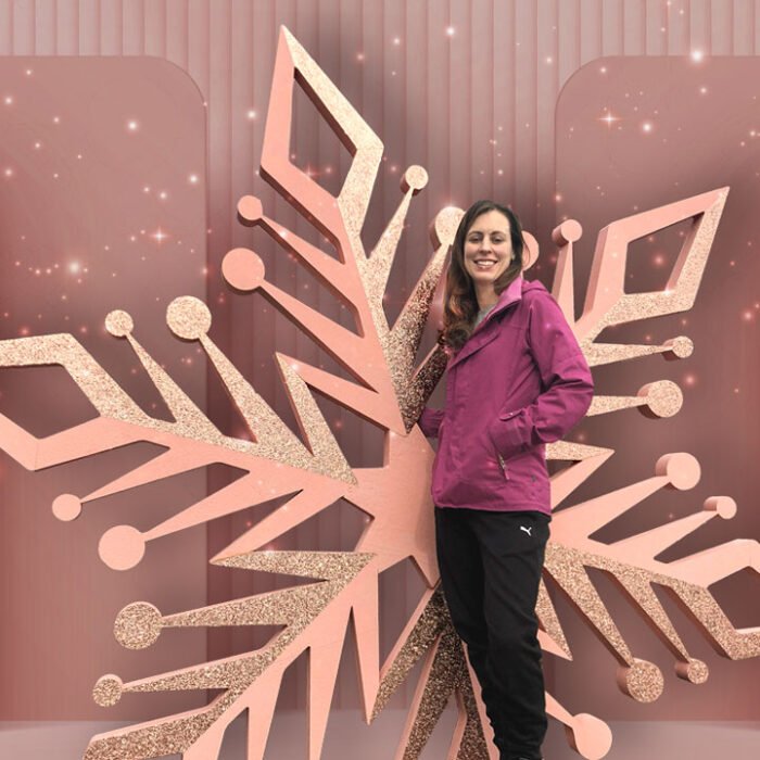 Woman posing in front of a giant snowflake prop. mall activations
