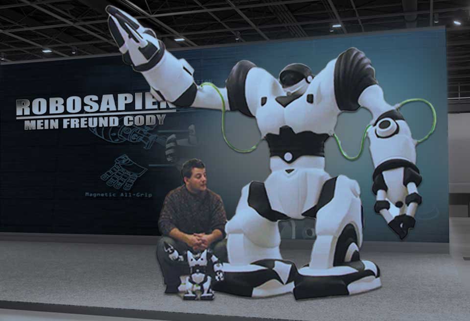 ROBOSAPIEN_PHOTO_OP Robosapien giant replicas robot next to a men and the actual 18 tall Robosapien toy.