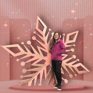 Woman posing in front of a giant snowflake selfie station.