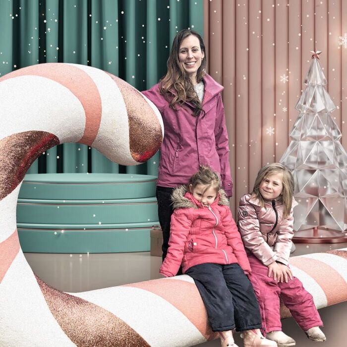 Mother with two kids posing on a large candy cane in a decor store. event photo op