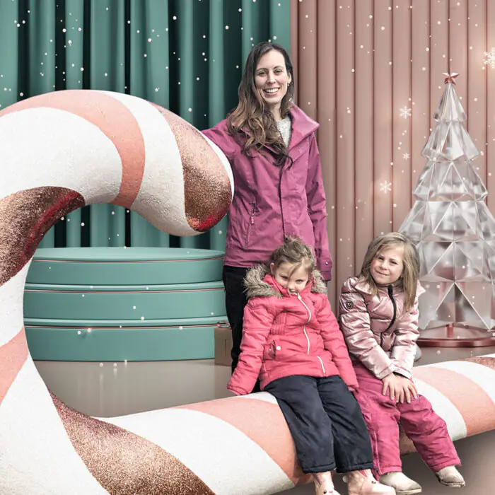 Mother with two kids posing on a large candy cane in a decor store. event photo op