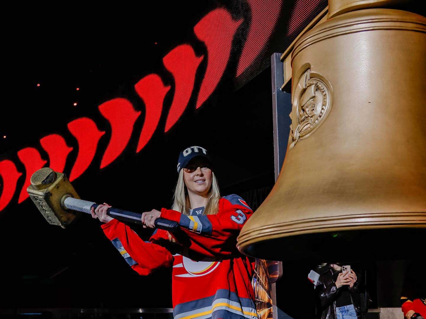 Senators_Woman_Mallet_Attempt_Bell Experiential marketing activations at NHL hockey games a woman attempts to hit a bronze bell with a mallet during an interactive fan experience activation.