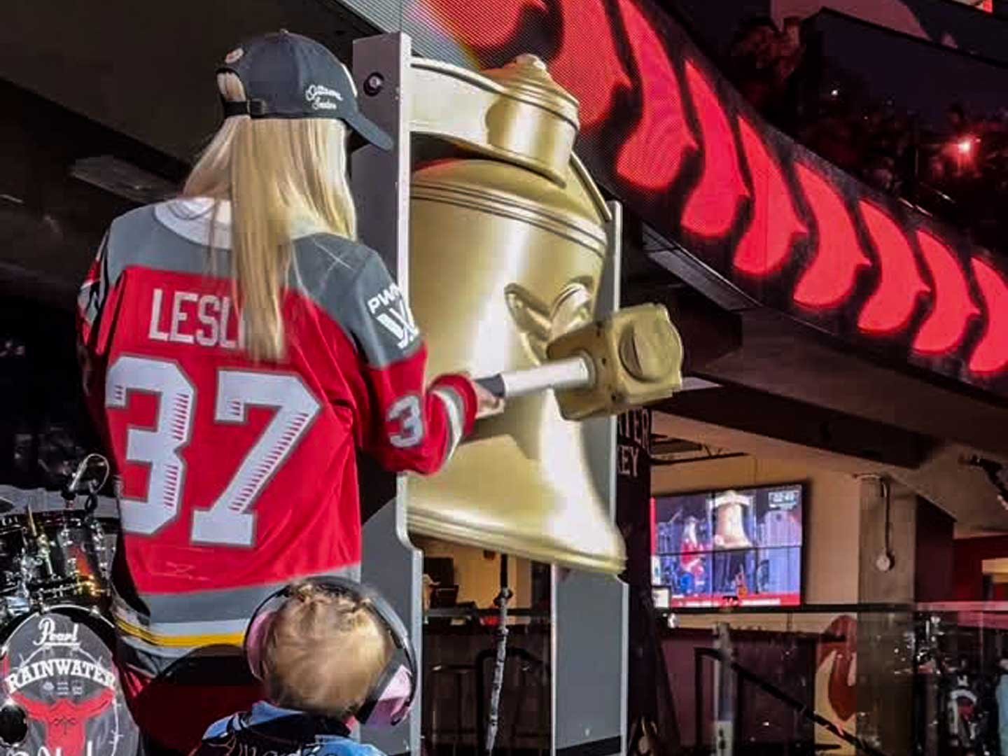 Senators_Woman_Mallet_Hits_Bell Woman hitting a bronze coloured bell with a mallet as part of an experiential display fan activation.