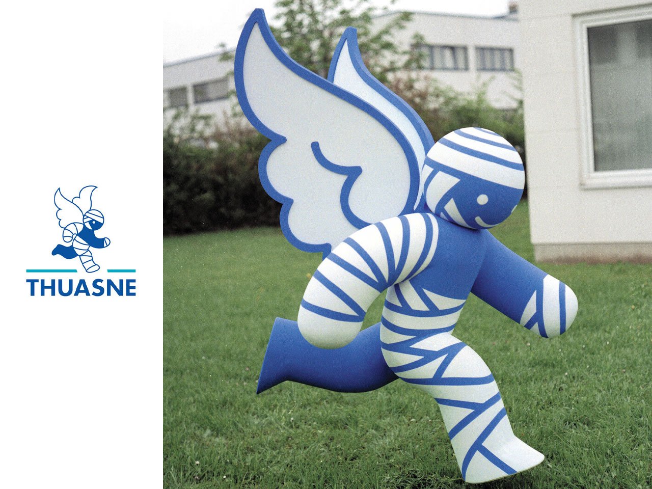 Thuasne logo with a blue winged mascot on the left and a large blue-and-white striped inflatable winged figure running on grass to the right. 2d to 3d logo