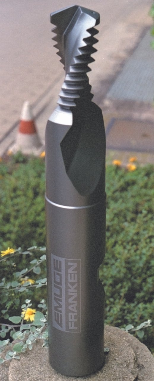 Emuge Franken Close-up of a black drill/tap with spiral cutting threads, standing upright outdoors mounted on a rock as sculpted signage.