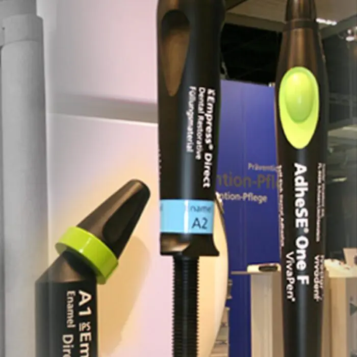 Display of dental handpieces and drill tips on a showroom shelf with Ivoclar Vivadent branding at bottom right.