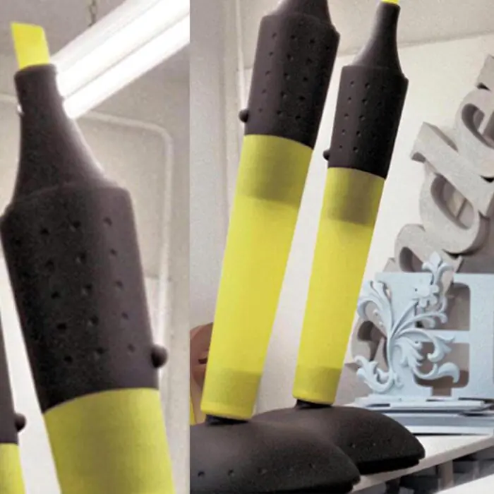 Close-up of yellow and black grip handles mounted on a horizontal bar; perforated black grips and a white label with text visible in the background.